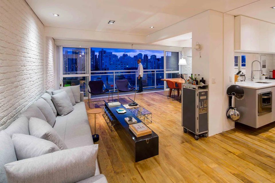 Uma sala com sofá, mesa, cadeiras e varanda.