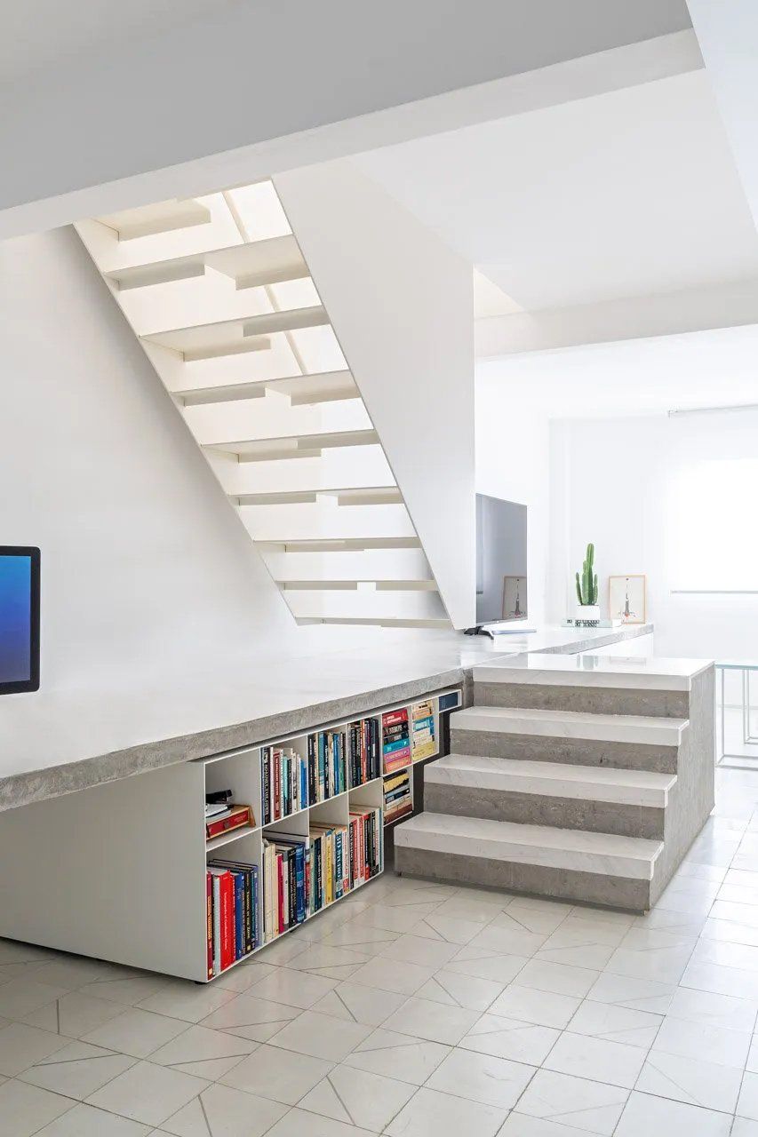 Uma escada com uma estante embaixo em uma sala de estar.