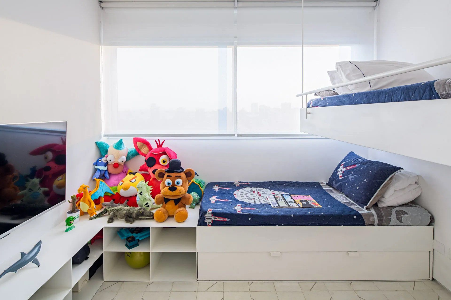 Um quarto com beliche, televisão e muitos bichinhos de pelúcia.