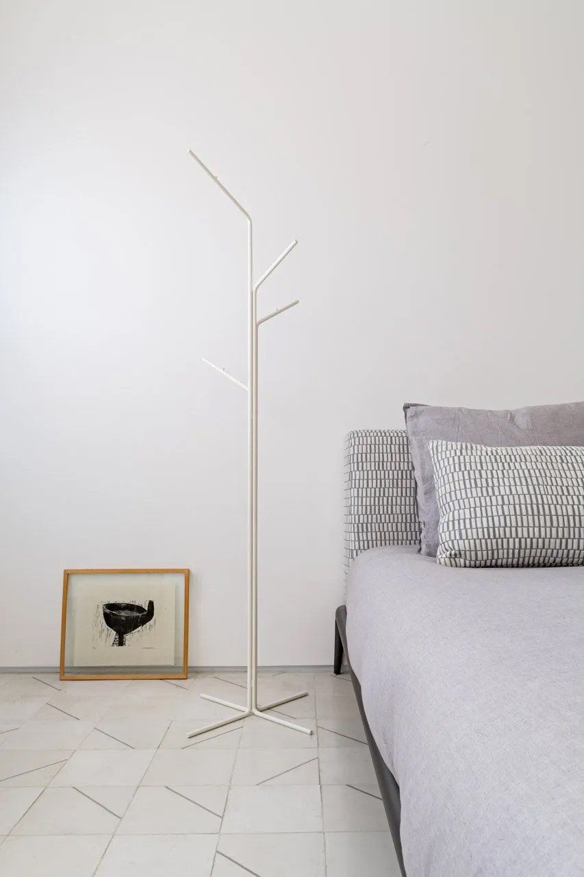 Um quarto com uma cama, um cabide e um quadro na parede.