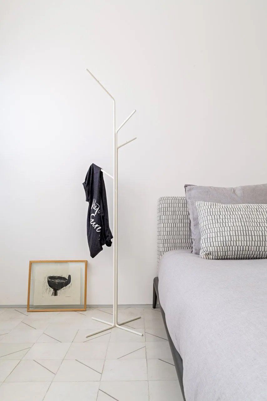 Um quarto com uma cama, um cabide e um quadro na parede.