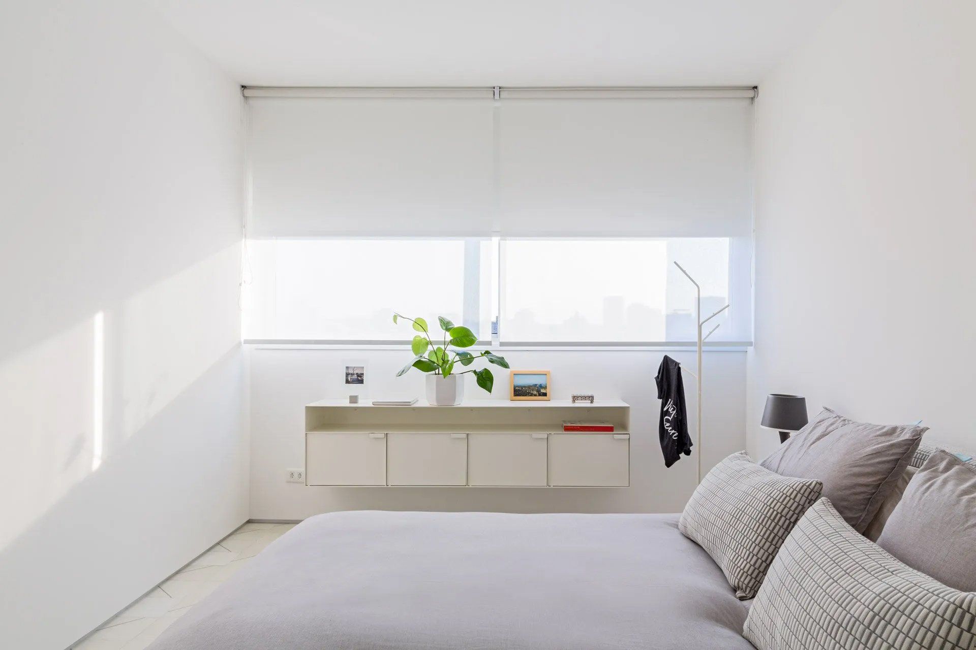 Um quarto com cama e janela com persianas brancas.