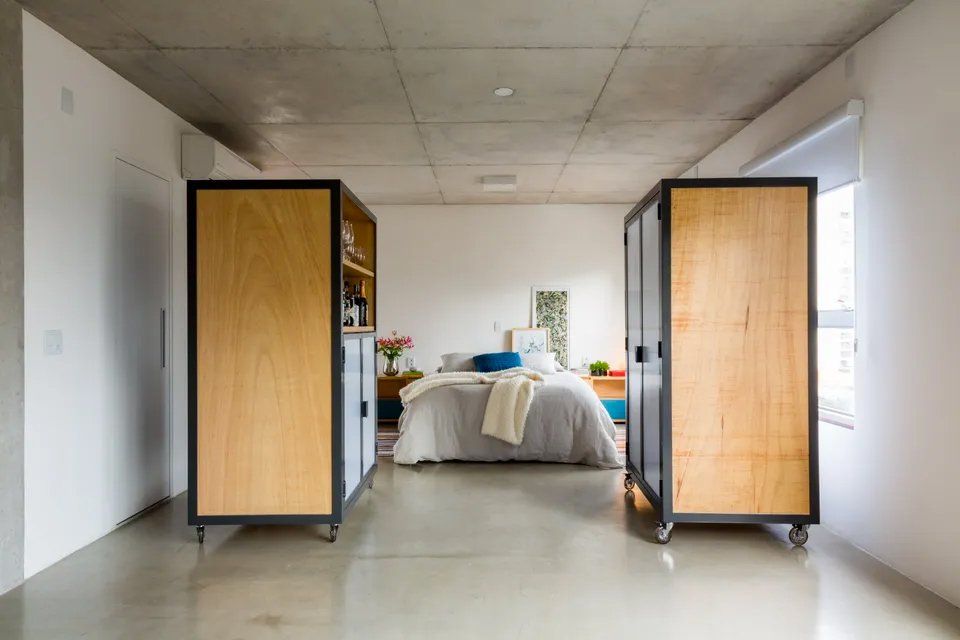 Um quarto com cama e dois armários de madeira sobre rodas.