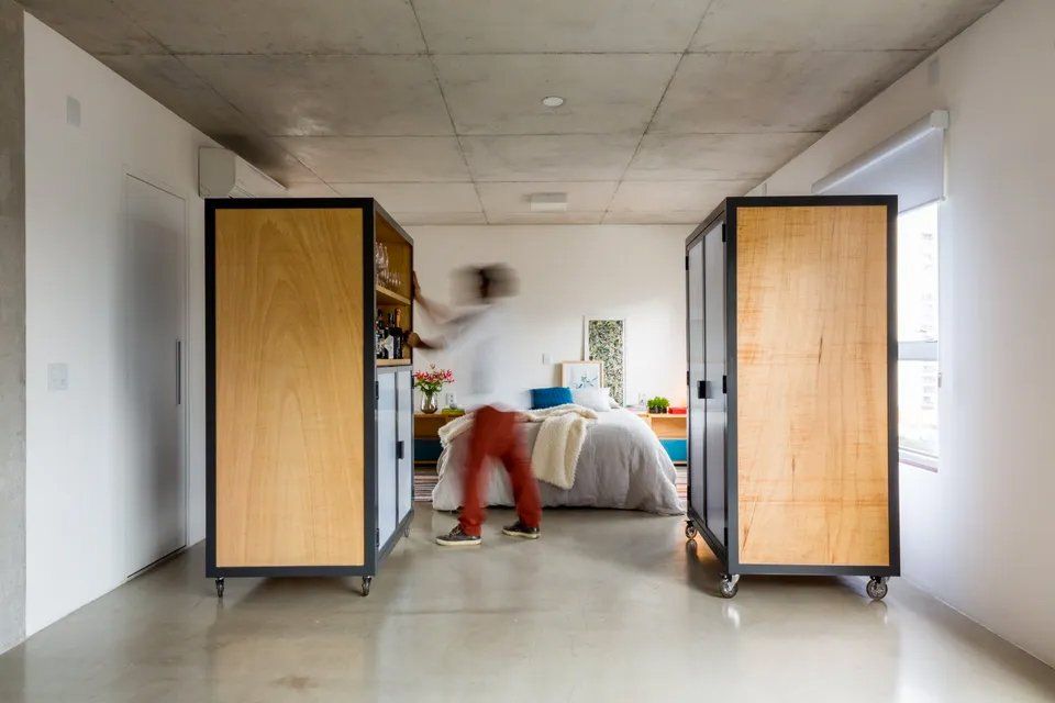 Um homem está parado em um quarto entre dois armários de madeira.