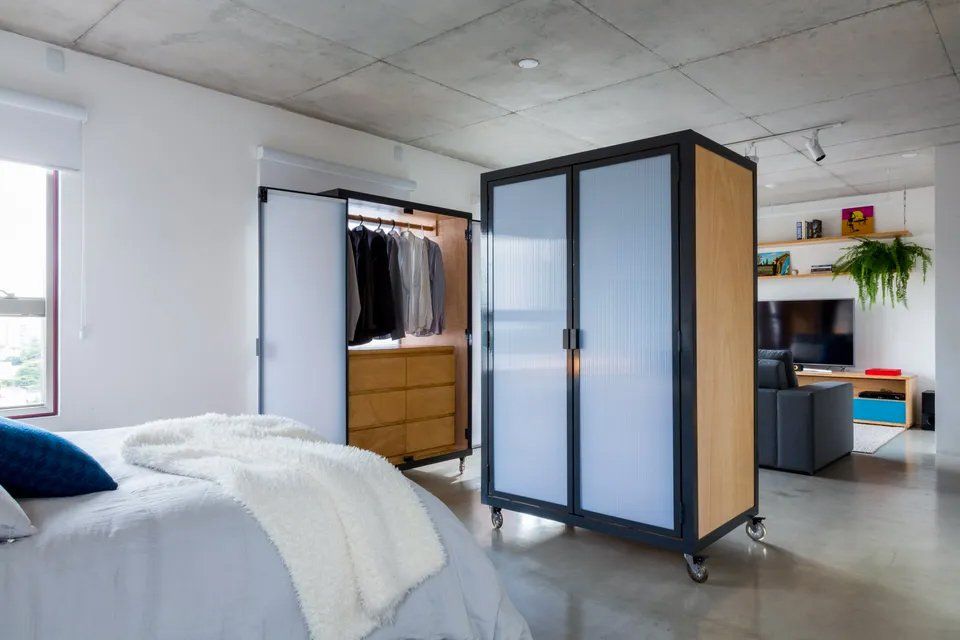 Um quarto com cama, cômoda e guarda-roupa.