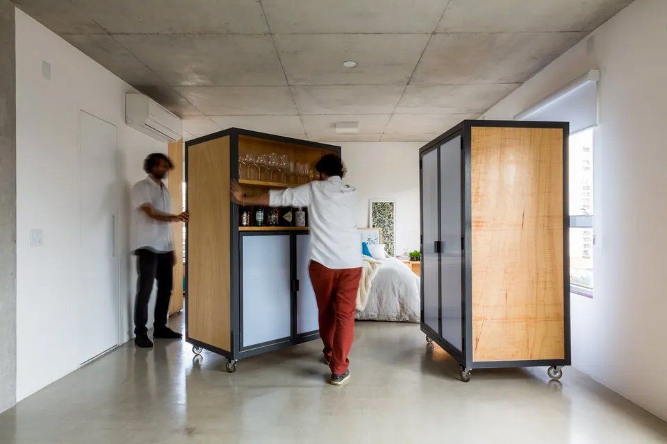 Um homem está parado ao lado de um armário de madeira em uma sala.