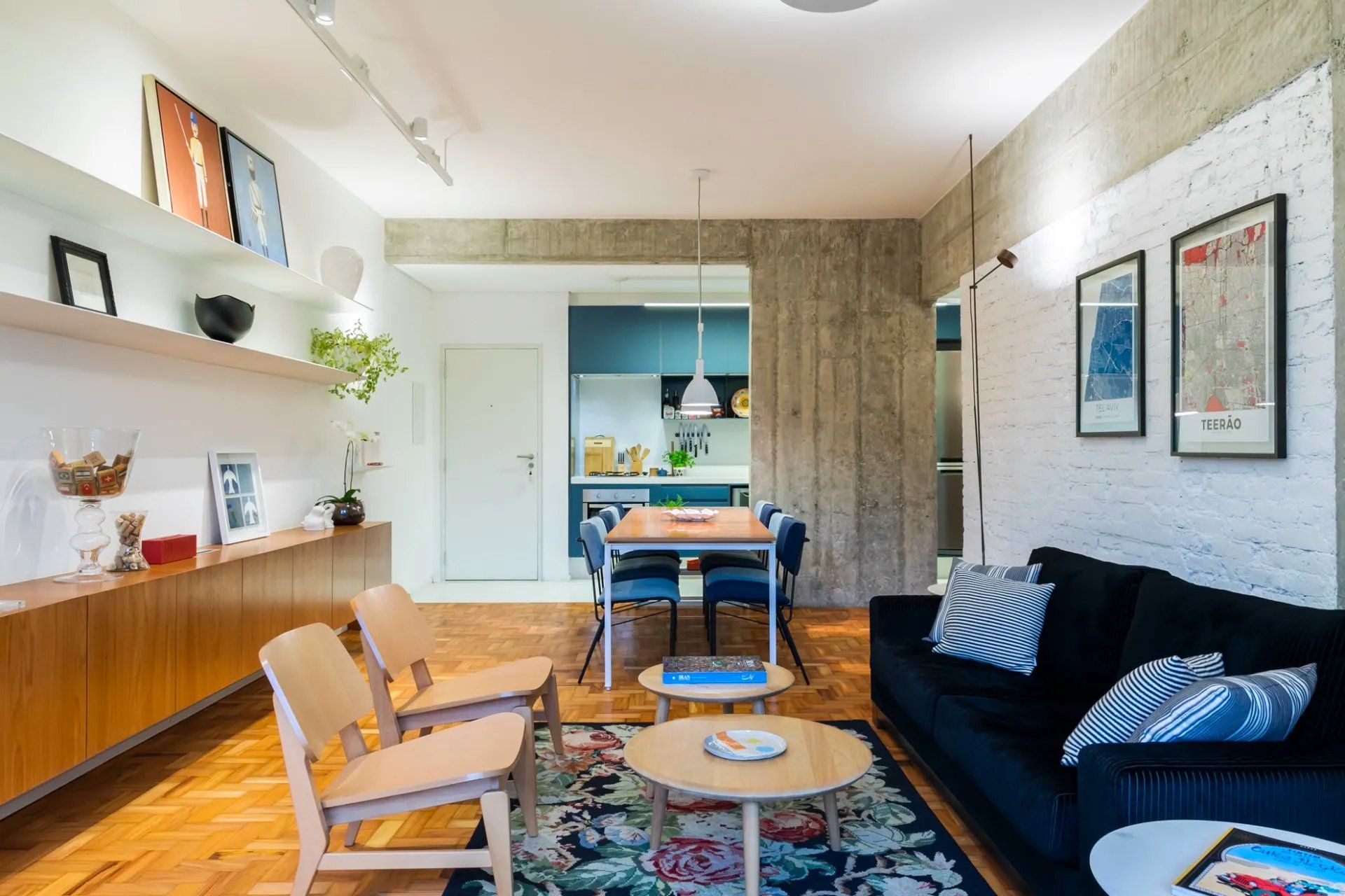 Uma sala com sofá preto, cadeiras, mesa e tapete.