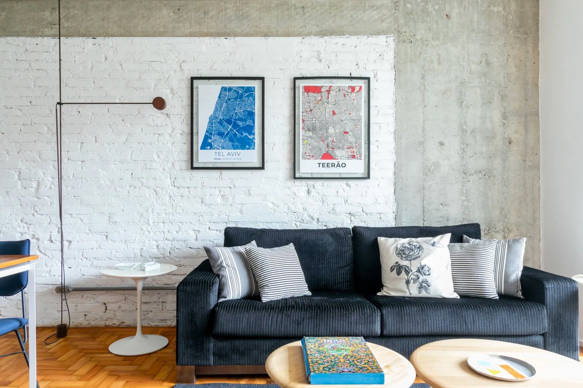 Uma sala com sofá preto e duas mesas de centro.