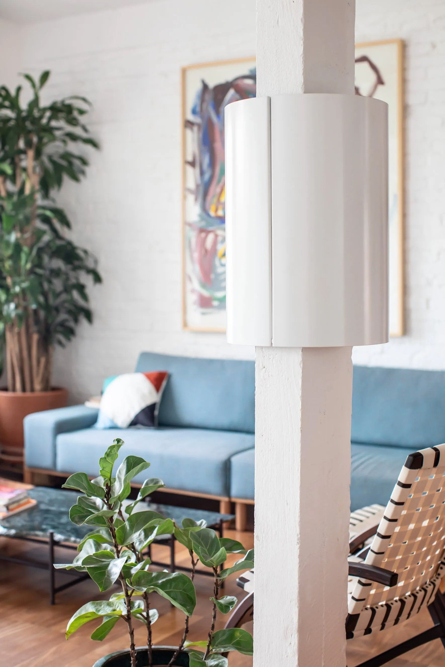 Uma sala com sofá azul, cadeira, mesa e vasos de plantas.