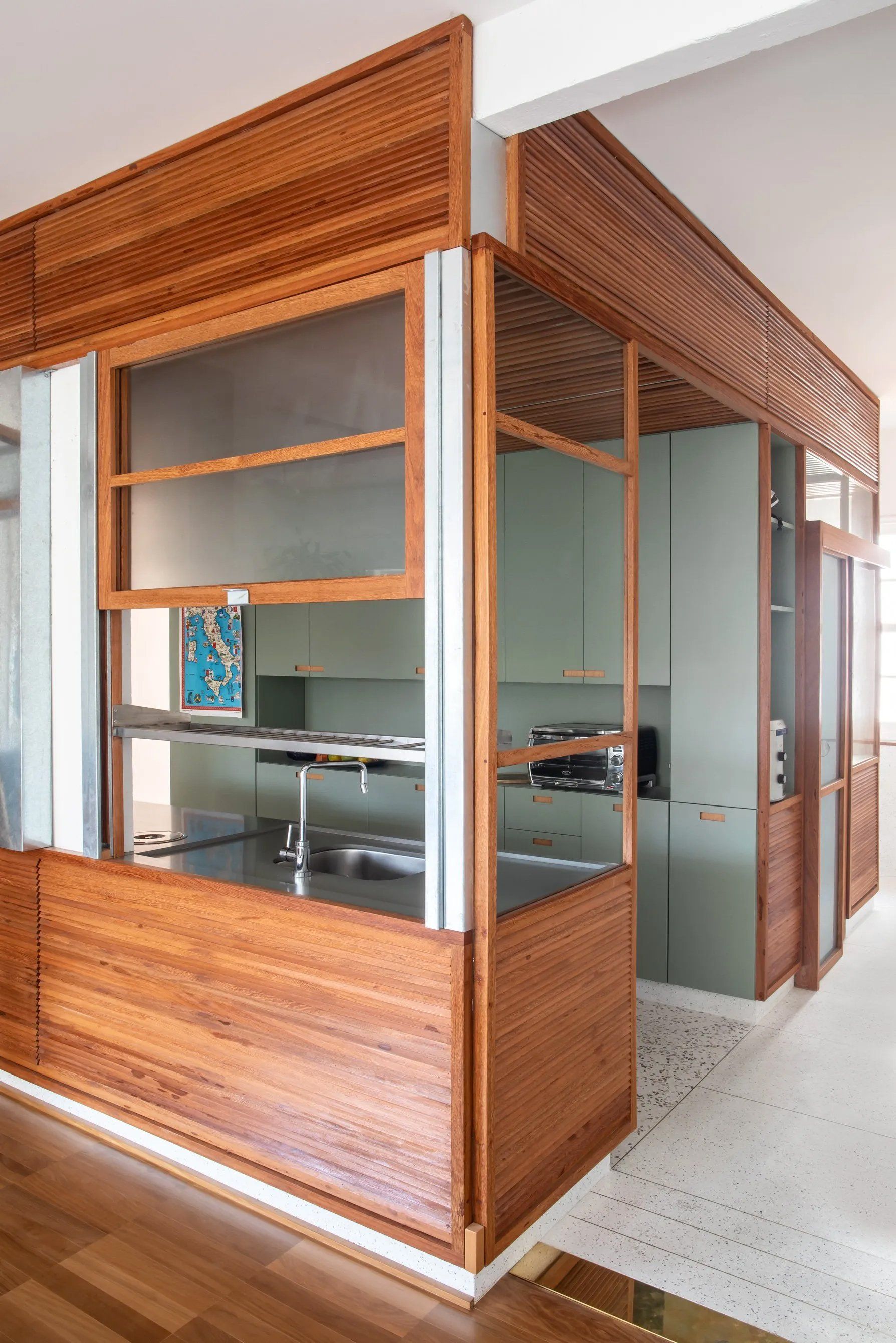 Uma cozinha com divisória de madeira entre a cozinha e a sala.