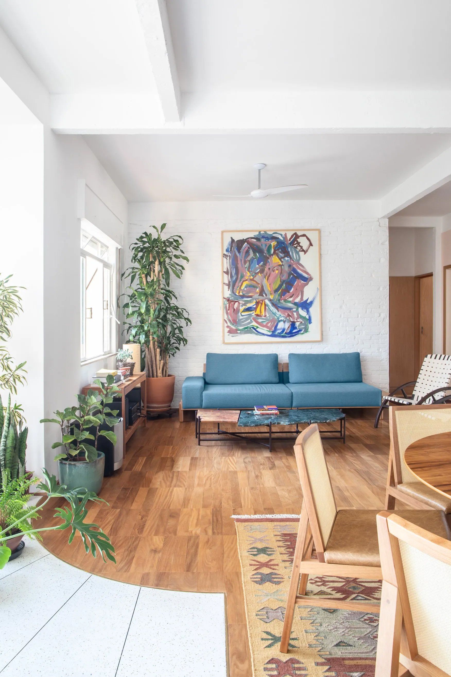 Uma sala com um sofá azul e um quadro na parede.