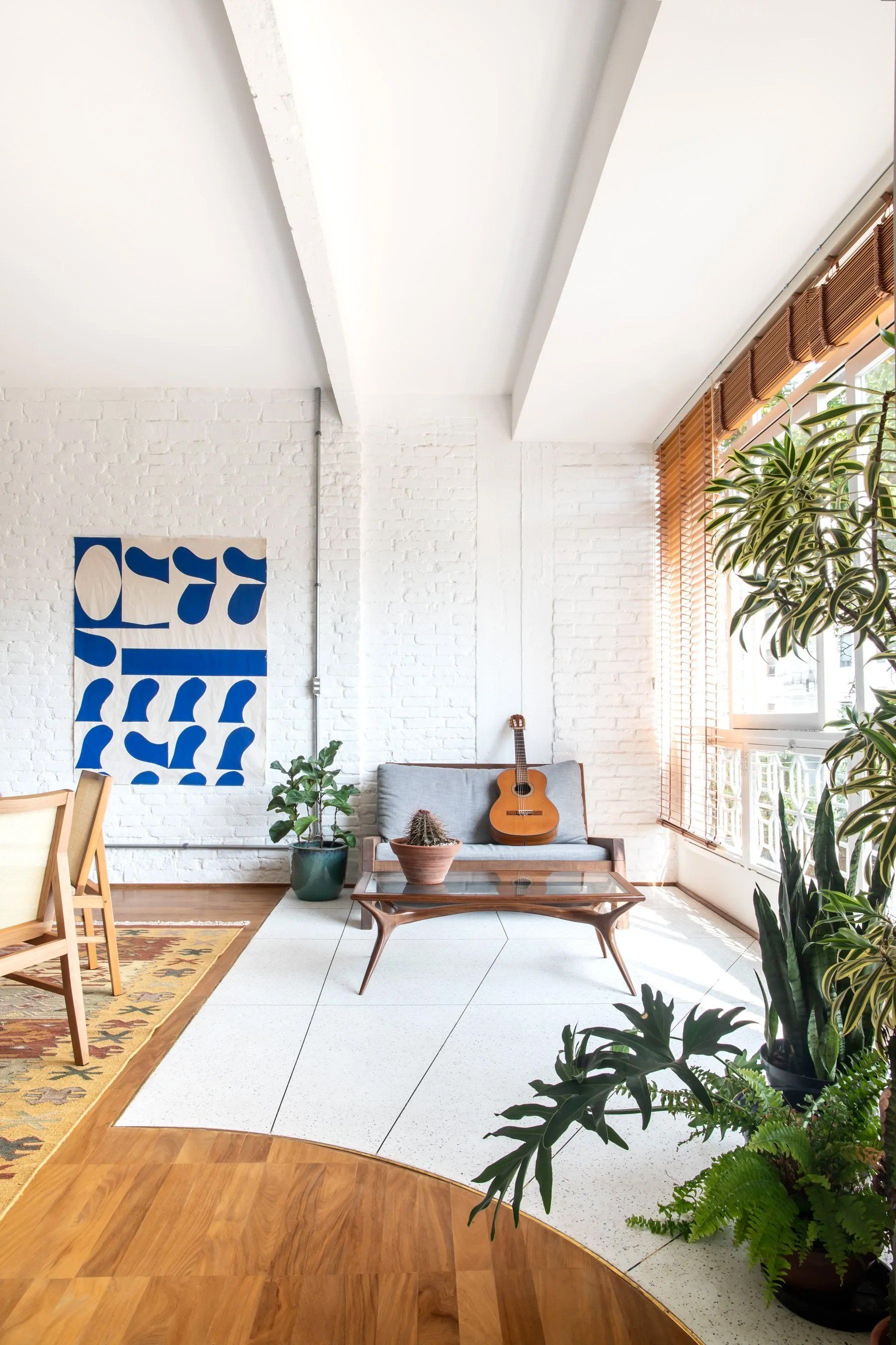 Uma sala de estar com sofá, mesa de centro e violão.