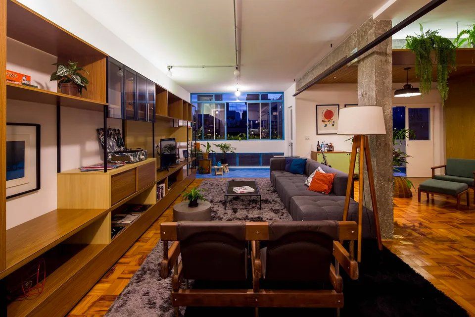 Uma sala de estar com sofá, cadeiras e luminária