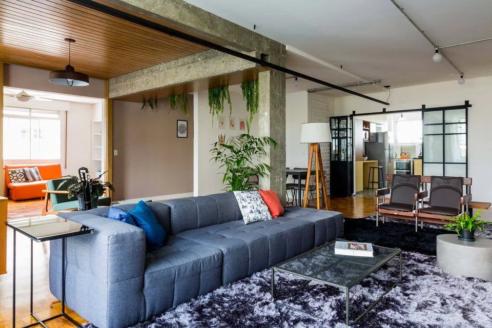 Uma sala de estar com sofá, cadeiras e tapete.