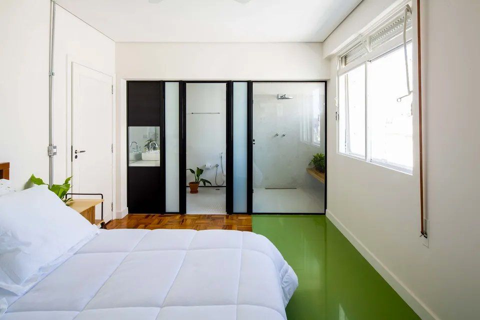 Um quarto com piso verde e cama branca