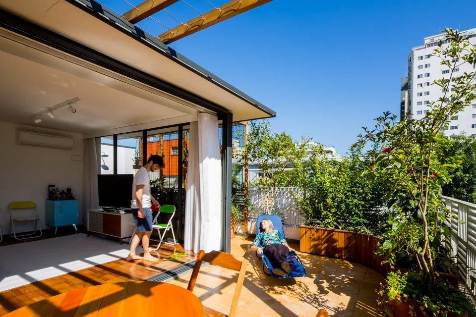 Um homem está parado em uma sala de estar ao lado de uma mesa e cadeiras.