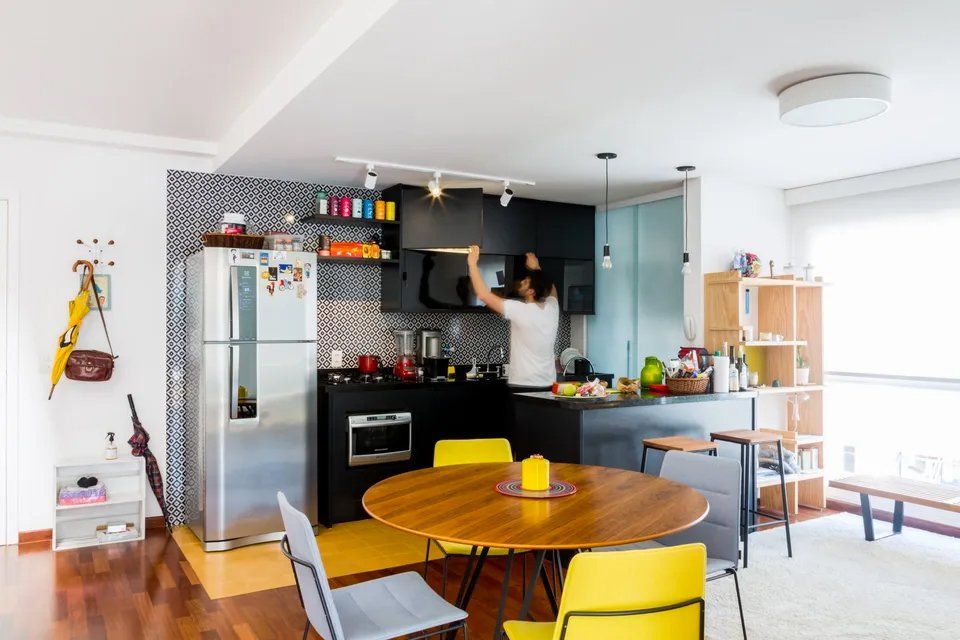 Uma mulher está cozinhando em uma cozinha com mesa e cadeiras.