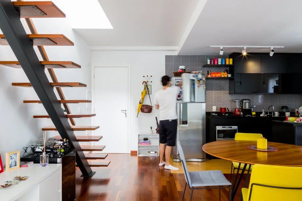 Um homem está parado em frente a uma geladeira na cozinha.