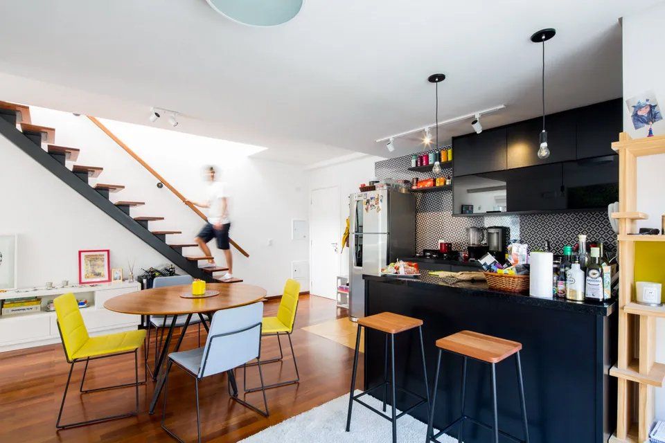 Uma cozinha com mesa e cadeiras e uma escada ao fundo.