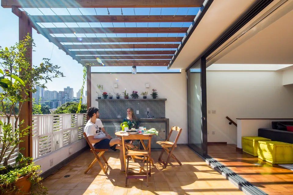 Um homem e uma mulher estão sentados em uma mesa na varanda.