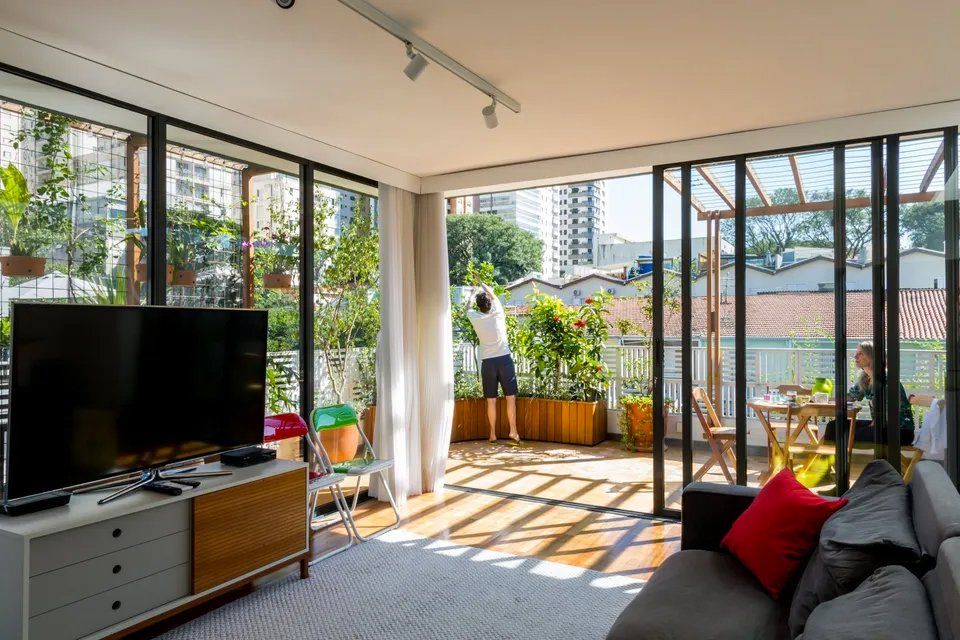 Uma sala de estar com sofá, televisão e varanda.