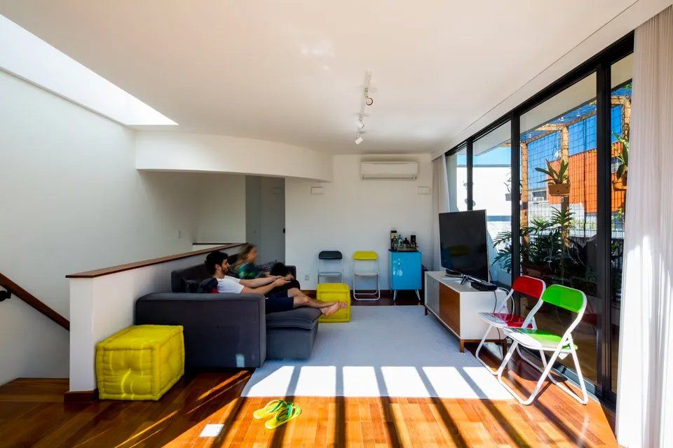 Uma sala de estar com sofá, cadeiras e televisão.