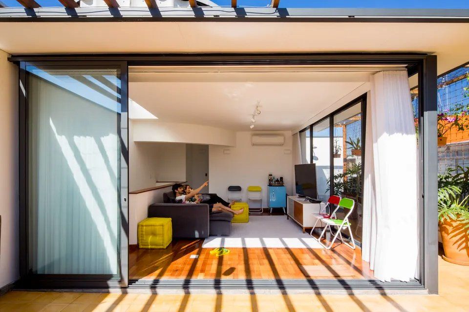 Uma mulher está sentada em um sofá em uma sala de estar com porta de vidro deslizante.