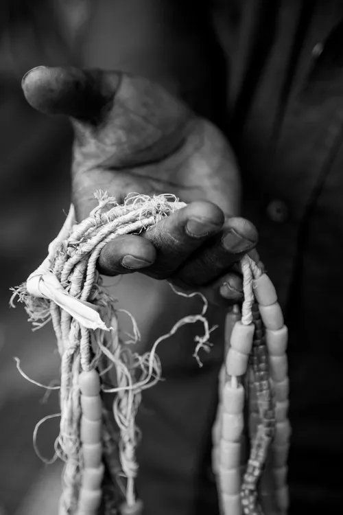 Uma foto em preto e branco de uma pessoa segurando um colar de contas