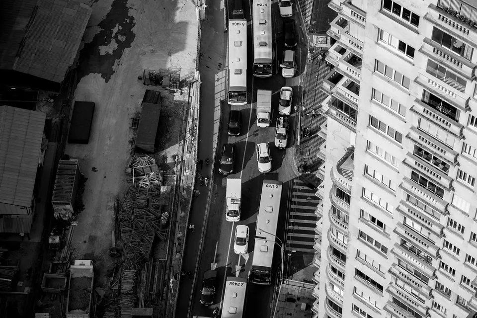 Uma foto em preto e branco de uma rua da cidade com um prédio alto ao fundo