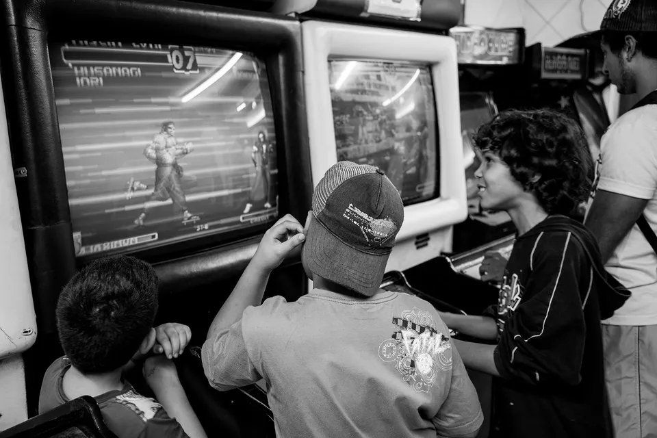 Um grupo de crianças está jogando videogame em uma foto em preto e branco.