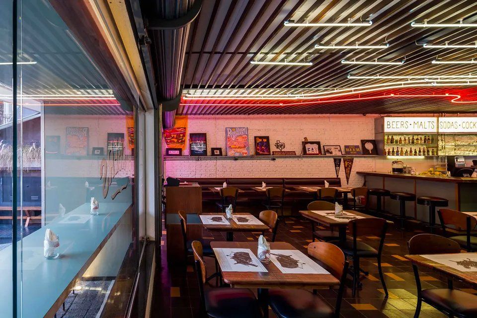 Um restaurante com mesas e cadeiras e um bar.