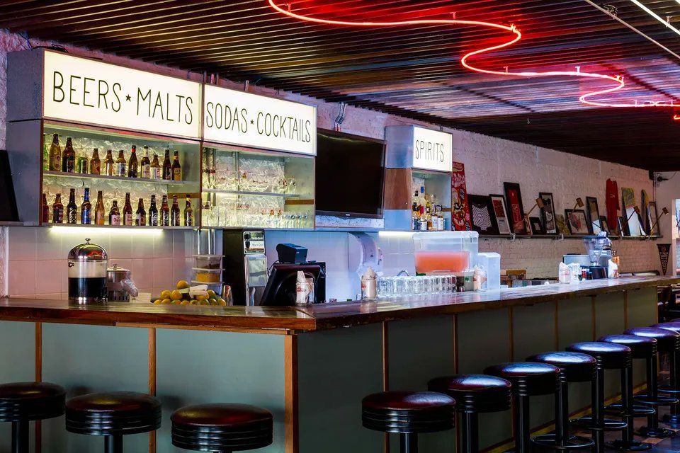 Um bar com um letreiro de néon que diz cerveja e maltes