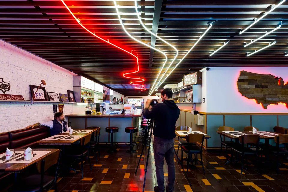 Um homem está tirando uma foto de um restaurante com luzes de néon