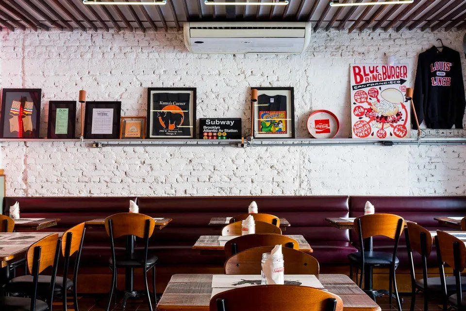 Um restaurante com mesas e cadeiras e uma parede de tijolos