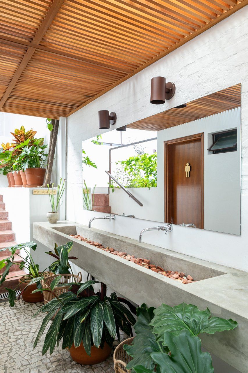 Um banheiro com duas pias, espelho e vasos de plantas.