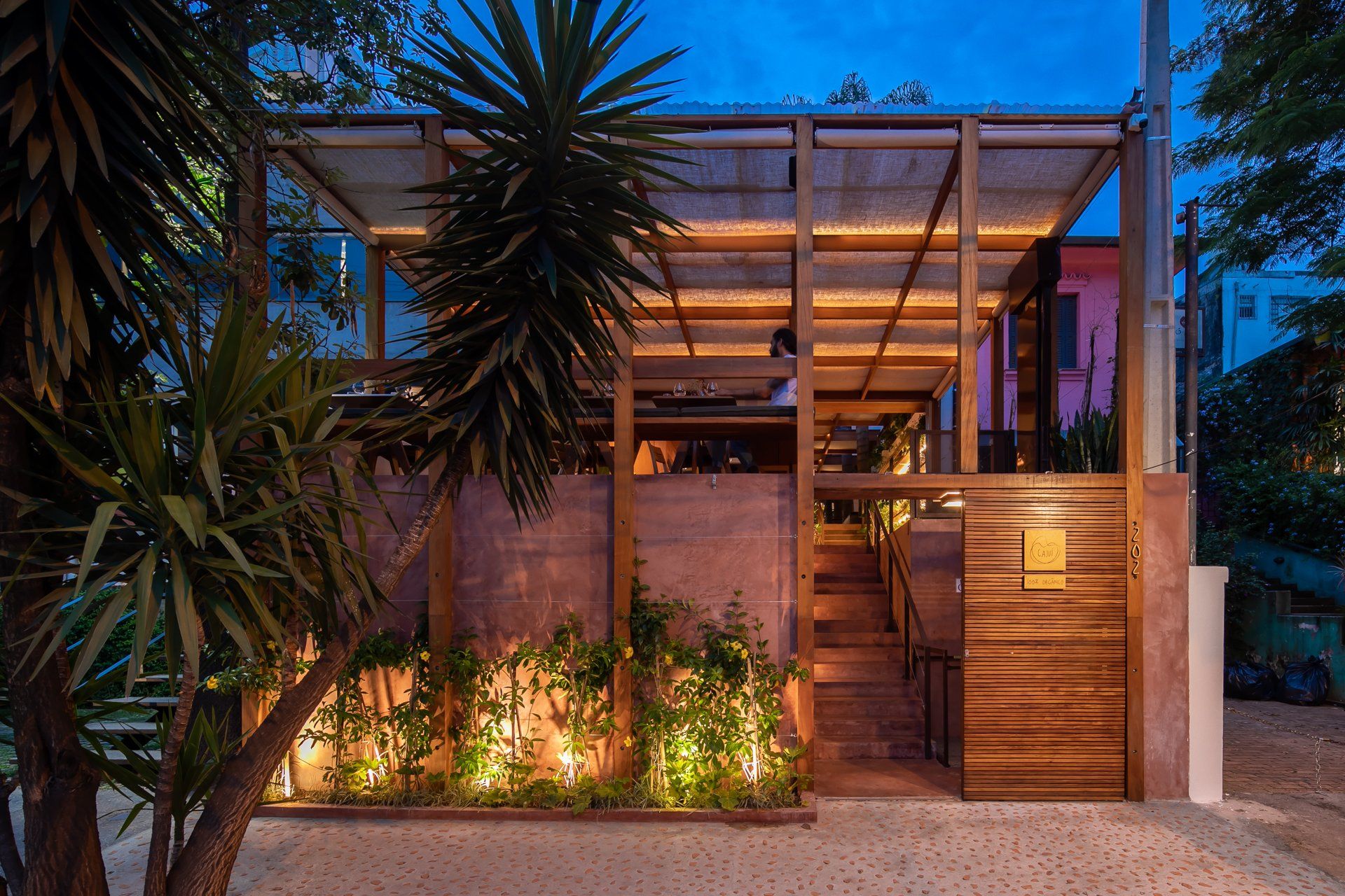 Um prédio com uma cobertura é cercado por árvores à noite.