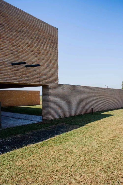 Uma grande parede de tijolos cerca um campo verdejante.