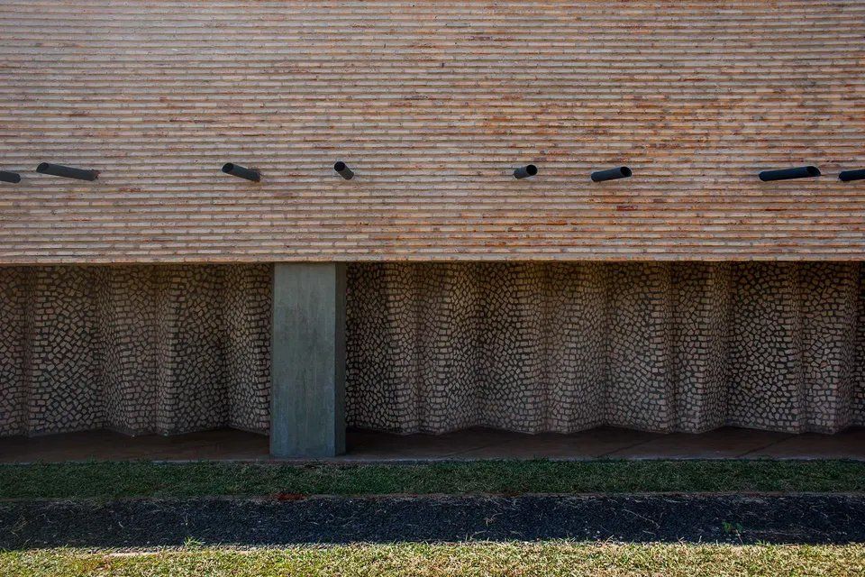 Uma parede de tijolos com um pilar de concreto na frente.