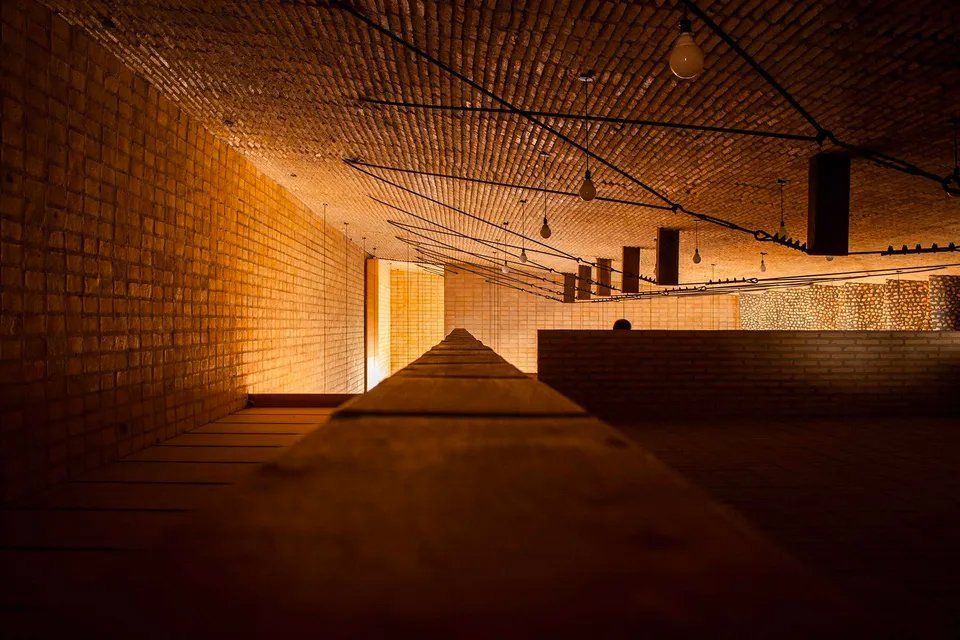 Um quarto escuro com parede de tijolos e piso de madeira.