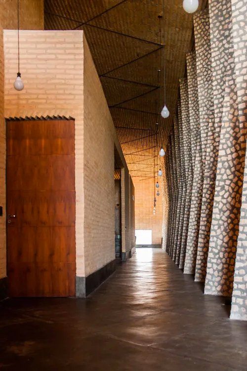 Um longo corredor com paredes de tijolos e uma porta de madeira.