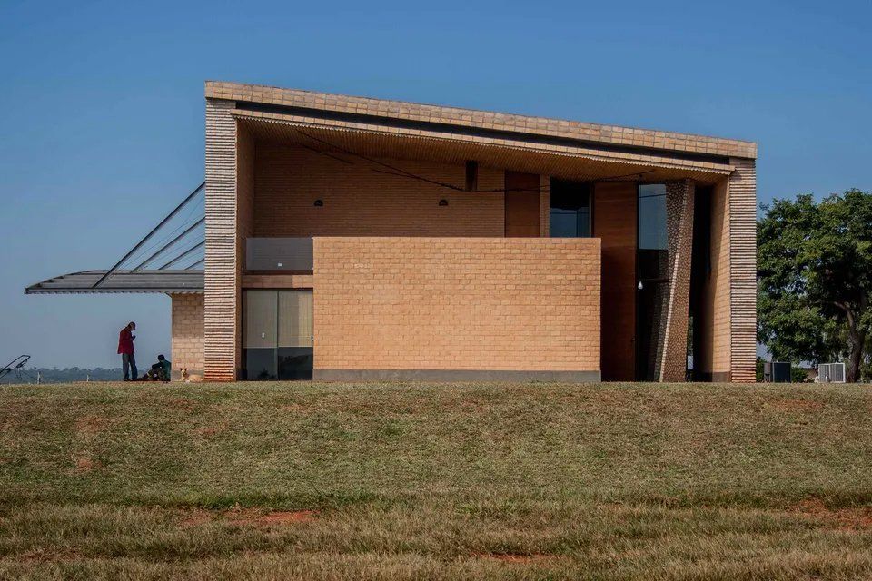 Um grande edifício de tijolos está situado no topo de uma colina gramada.