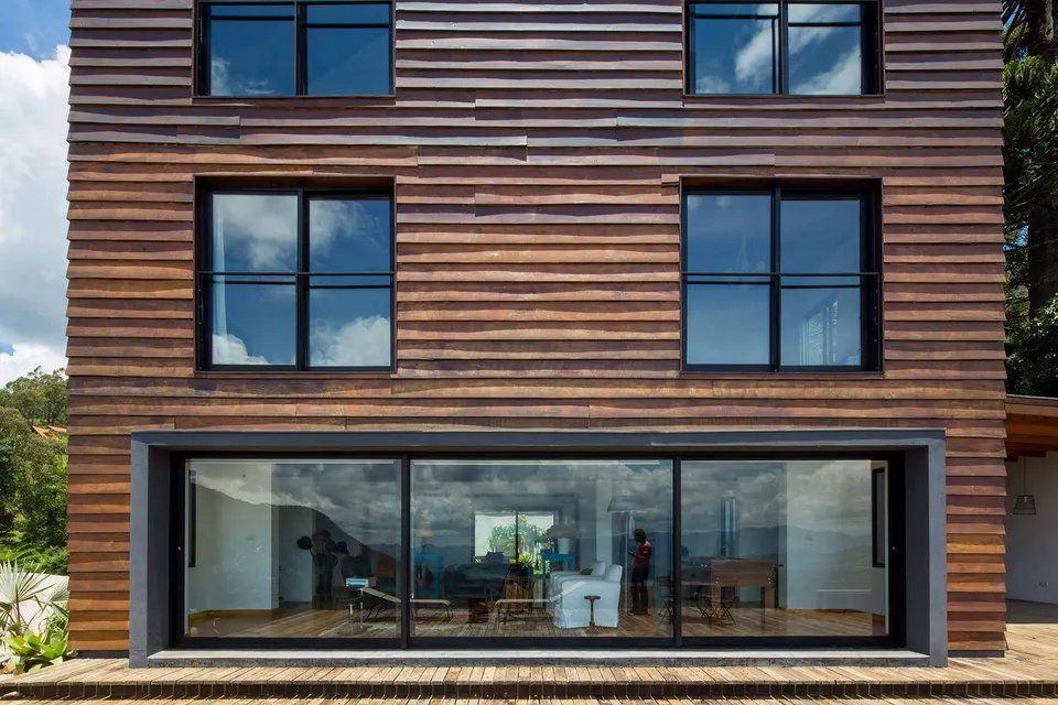 Uma casa grande com muitas janelas e fachada de madeira.