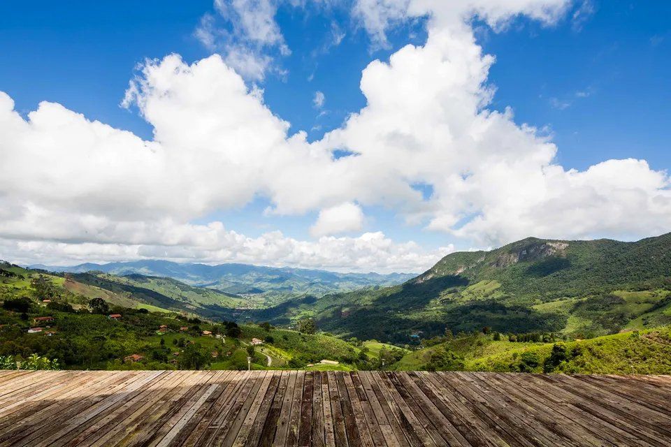 Uma mesa de madeira com vista para um vale e montanhas ao fundo.