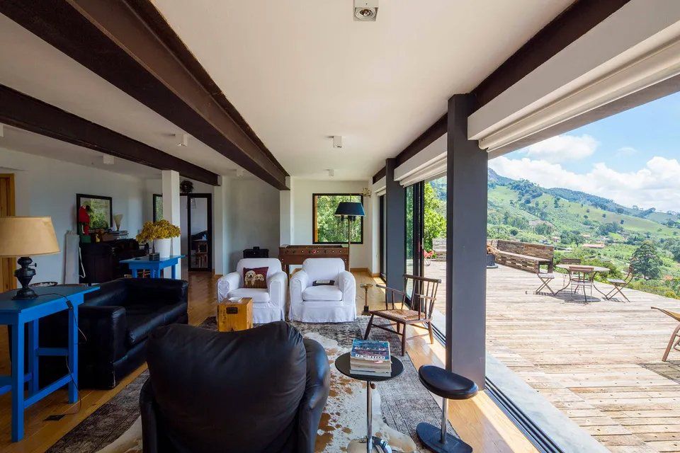 Uma sala com muitas janelas e vista para a serra.