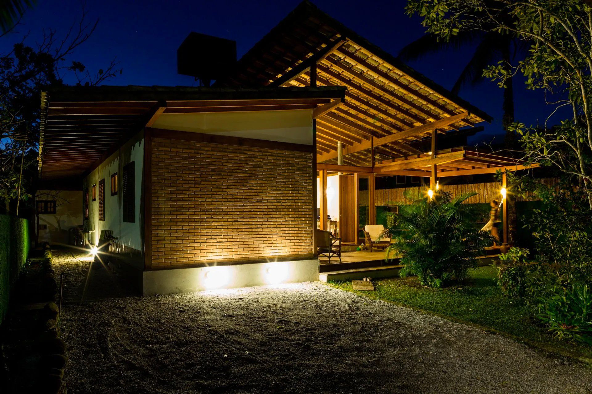 Uma pequena casa com telhado de madeira fica iluminada à noite.