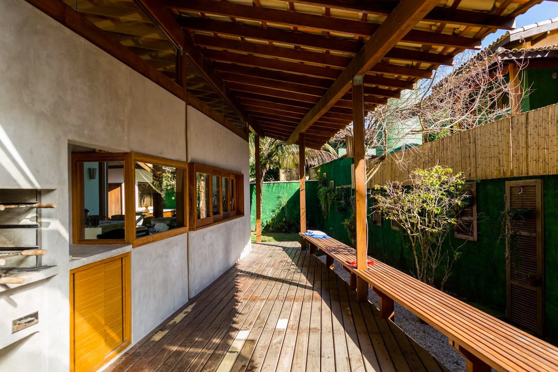 Uma varanda de madeira com uma mesa de madeira sob um telhado de madeira