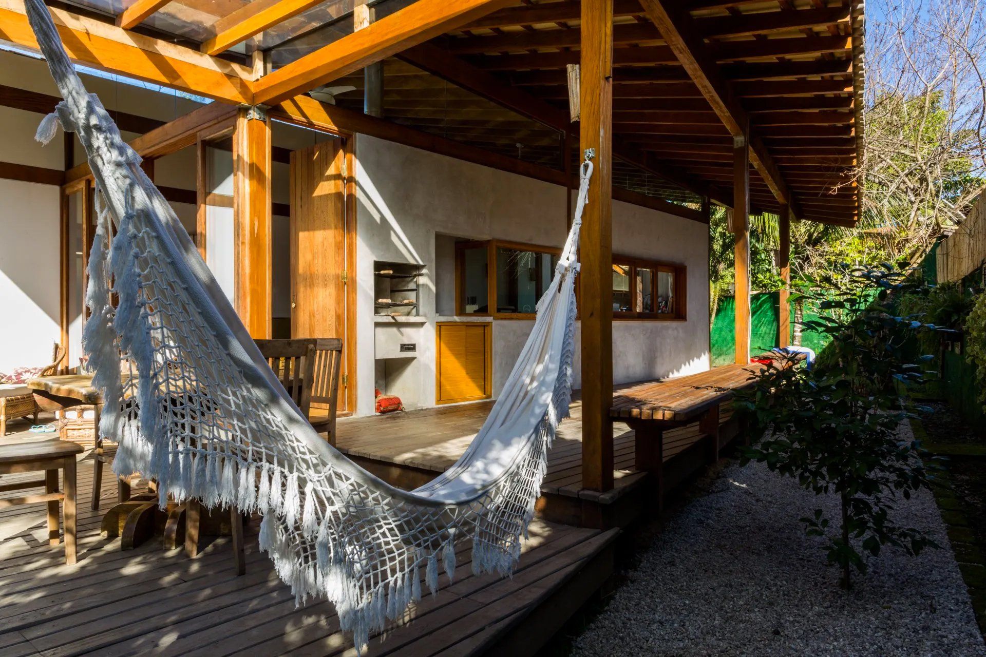 Uma rede está pendurada em um deck de madeira em frente a uma casa.