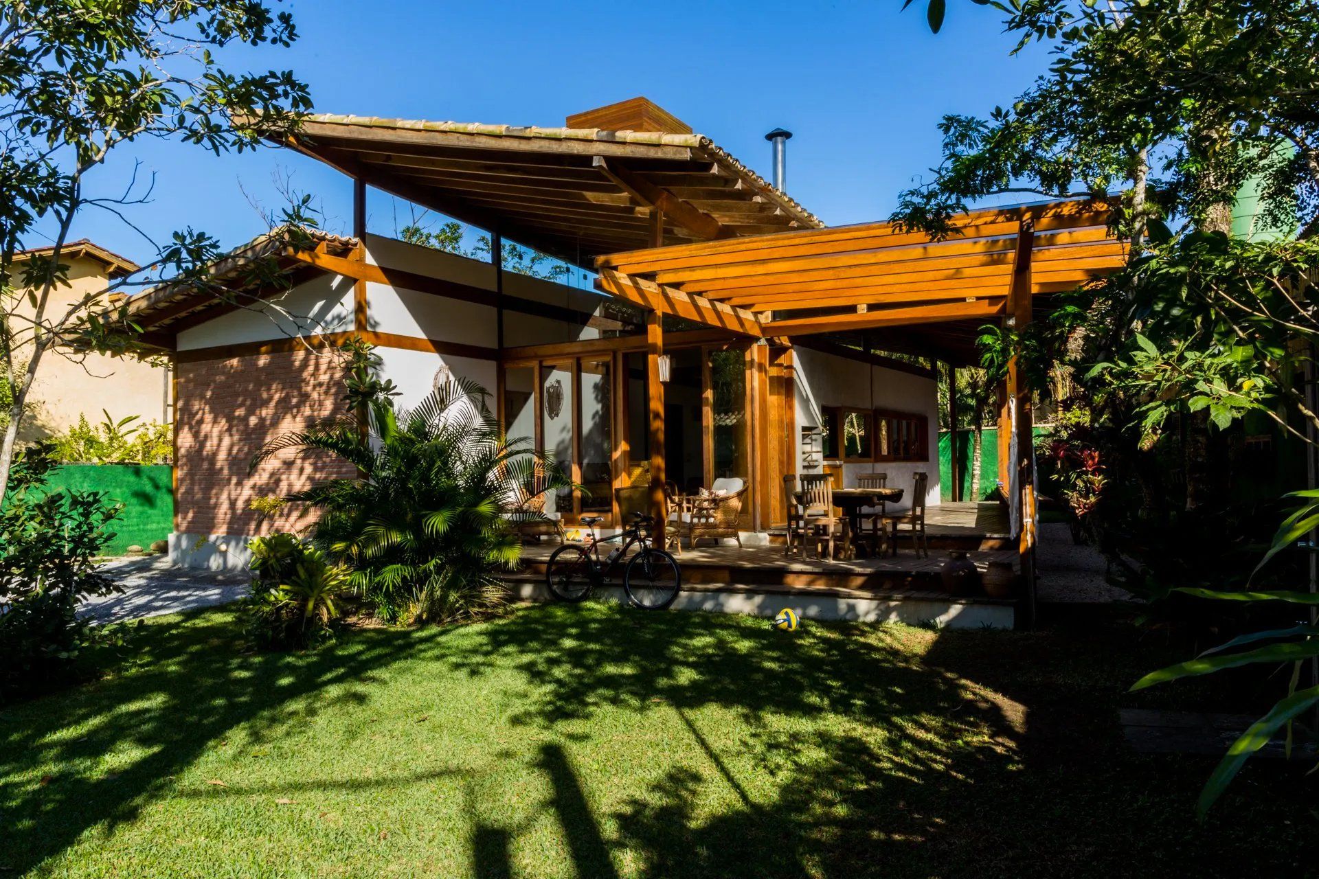 Uma casa com pergolado de madeira no quintal