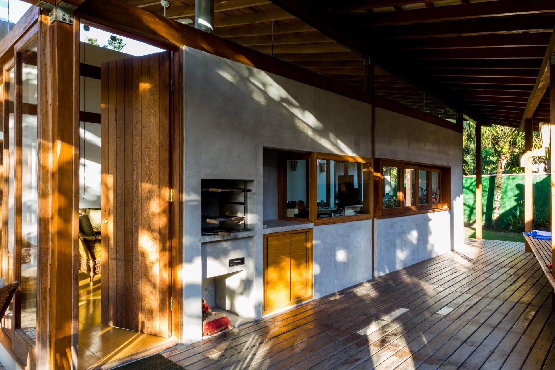 Uma casa com deck de madeira e churrasqueira no quintal