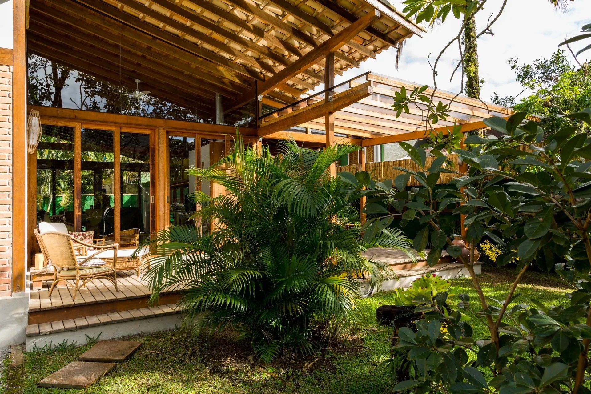 Uma casa de madeira com deck e cadeiras no quintal.